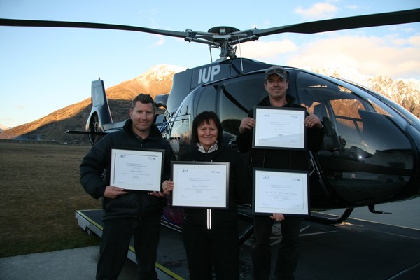 Stephen Beck, Louisa Patterson and Stuart Robinson pictured with their awards in front of a Over the Top Eurocopter EC130